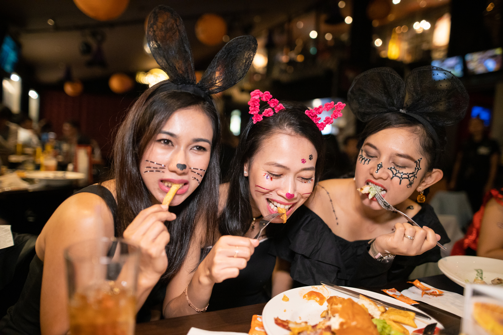 Asian women in halloween costume eating dinner at restaurant together