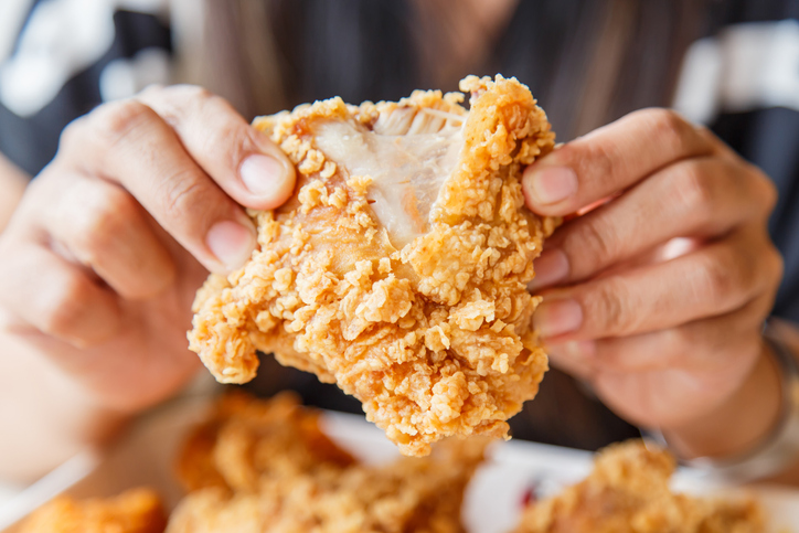 Hand holding Fried chicken and eating in the restaurant