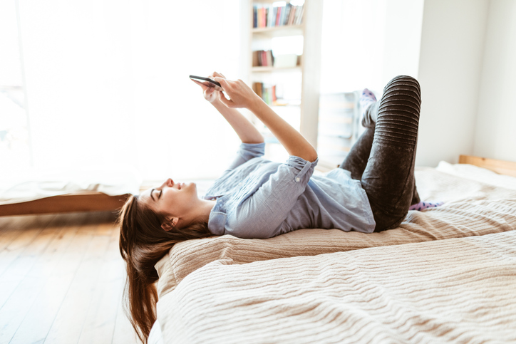 teenager text messaging on the phone in the bedroom