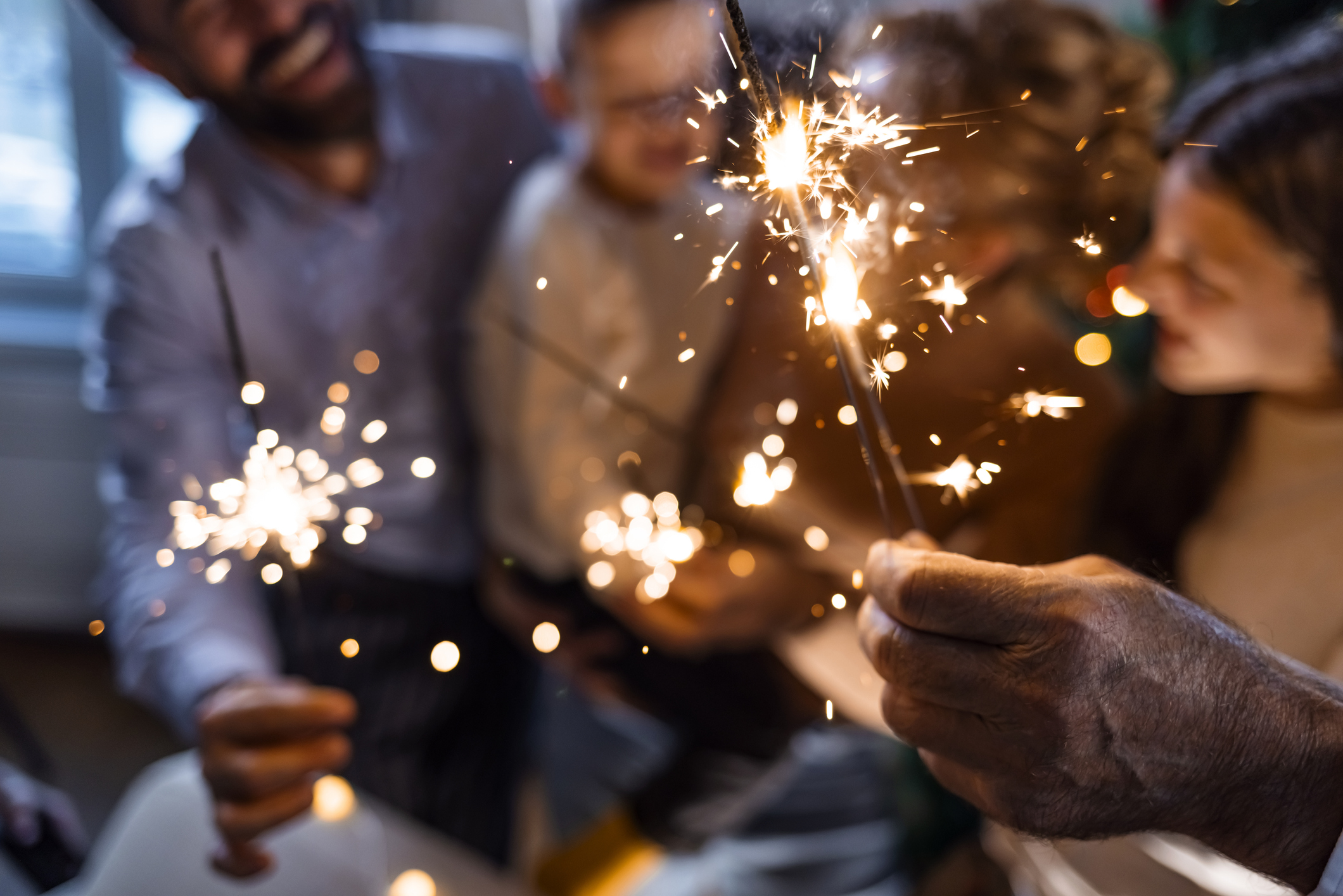 Happy new year! Family in living room during Christmas holidays, holding sprinklers